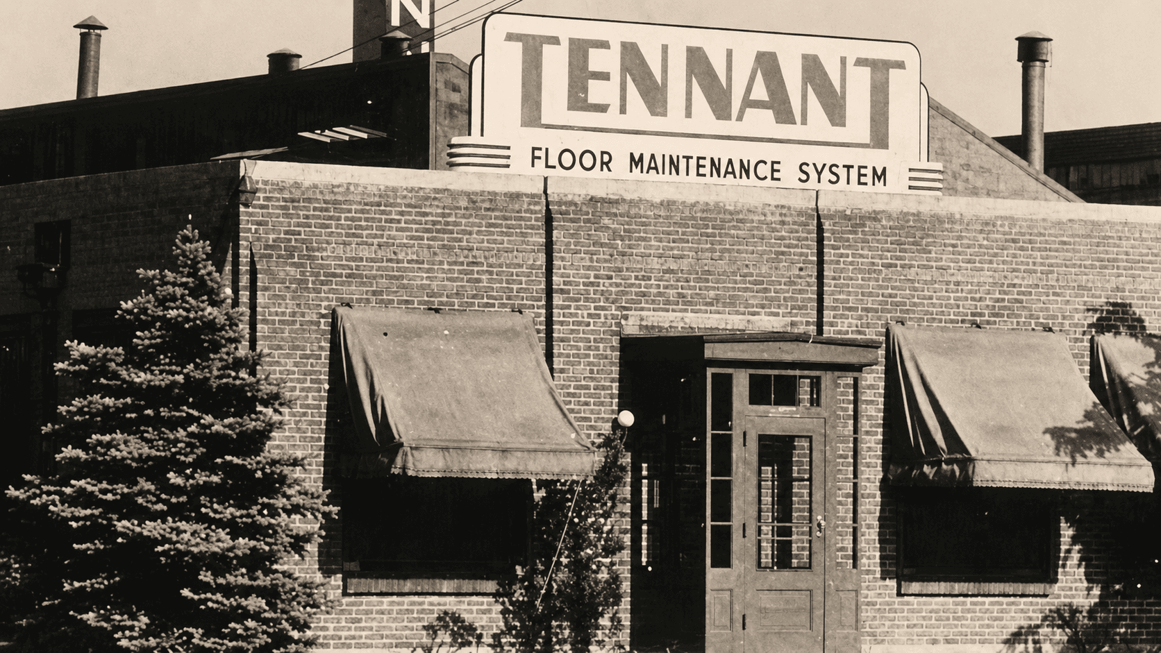 Fachada histórica de la fábrica Tennant, con el cartel "Floor Maintenance System"